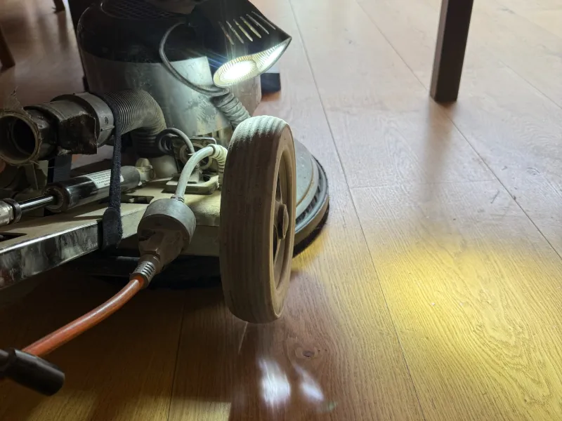 Close-up of a professional dust-free floor sanding machine being used on timber floorboards in a London home